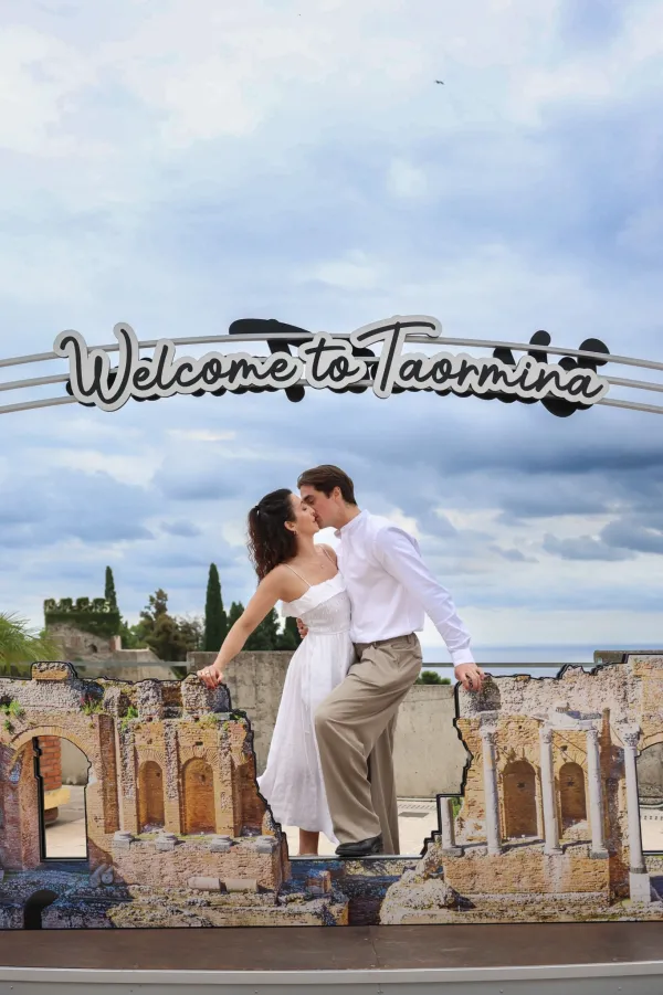 016-couple-smiling-under-welcome-to-taormina-sign