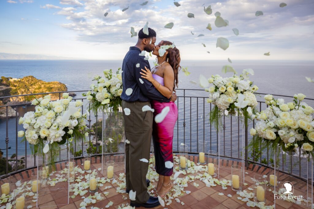 coppia innamorata sulla terrazza a Taormina – proposta di matrimonio al tramonto Coppia innamorata che si bacia con pioggia di petali su una terrazza sul mare a taormina