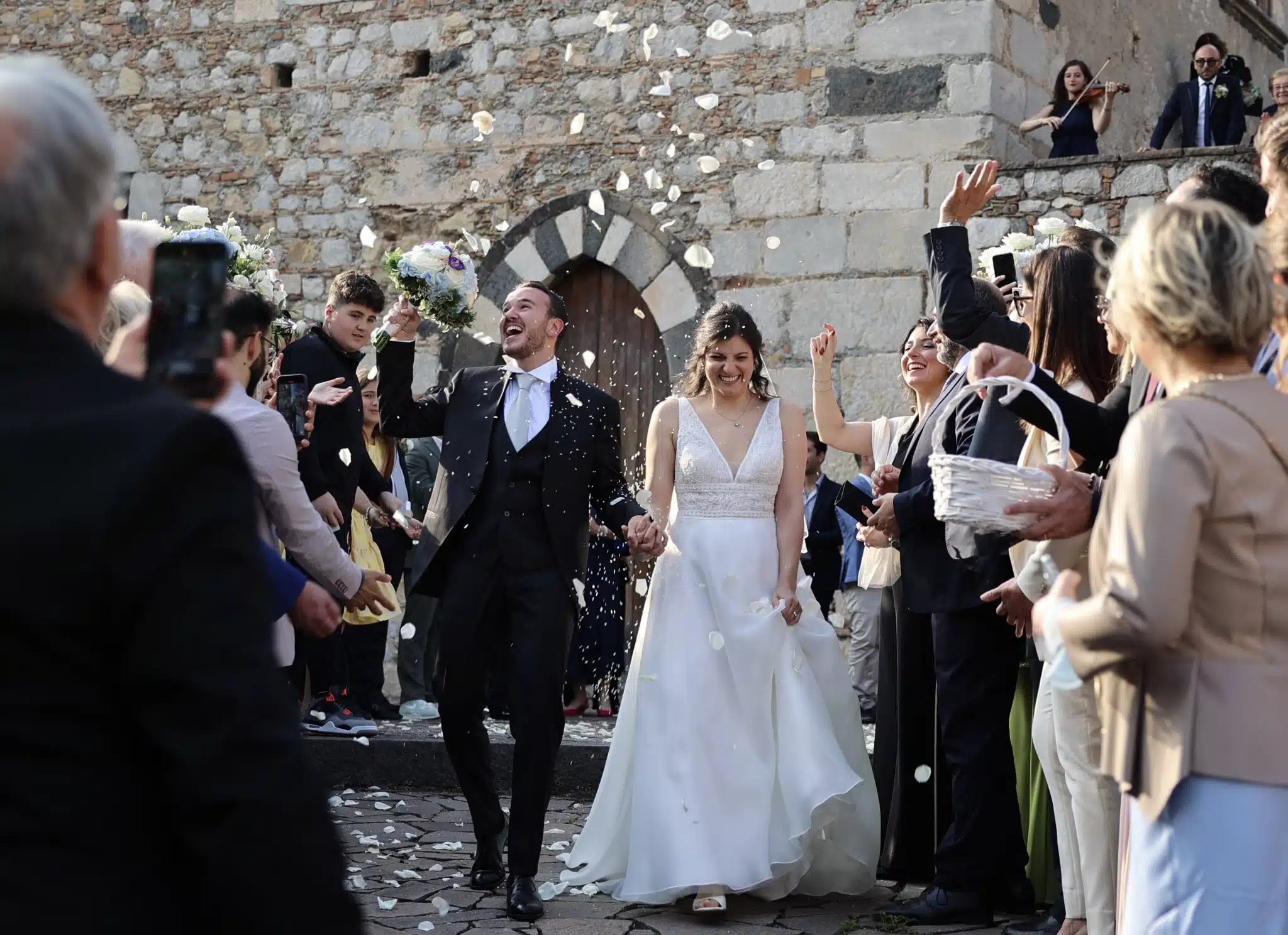Couple celebrating their wedding ceremony exit with rice in Taormina, Sicily