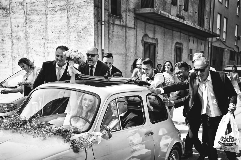 Joyful wedding celebration with vintage car photographed in Sicily
